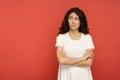 Sarcastic doubtful woman judgmental look with skeptical face aside to empty copy space over red wall