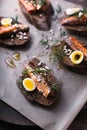 Sardines, quail egg on rye bread top view