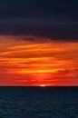 Sardinia. Sunset on the Mediterranean sea from the coastline of the Sulcis region. Orange and red light across the cloudy sky