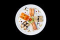 Sashimi set on a white round plate, decorated with small flowers, Japanese food. Top view. Isolated on a black Royalty Free Stock Photo