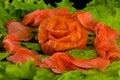 Sashimi syake with salmon slices arranged in form of rose, lemon slices, wasabi and lettuce leaves on a rectangular plate, closeup