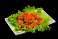 Sashimi syake with salmon slices arranged in form of rose, lemon slices, wasabi and lettuce leaves on a rectangular plate,