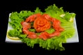 Sashimi syake with salmon slices arranged in form of rose, lemon slices, wasabi and lettuce leaves on a rectangular plate,