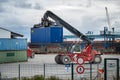 Sassnitz-Mukran, Germany, August 20, 2020: Red shunting vehicle is moving a heavy blue container in the industrial cargo port of