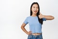 Sassy brunette asian girl winks, shows thumbs up to recommend product, advertising smth good, standing in blue tshirt