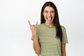 Sassy brunette woman looking happy, showing rock on heavy metal horns gesture, sticking tongue, enjoying event or party