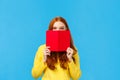 Sassy and creative happy charismatic redhead woman, teenager hiding face behind red notebook and smiling, grinning sly