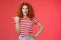 Sassy good-looking emotive happy smiling redhead european female curly hairstyle pointing thumb left grin assertive Royalty Free Stock Photo