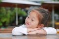 Sassy little Asian child girl with funny face lying on the wooden table Royalty Free Stock Photo