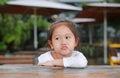 Sassy little Asian child girl with funny face lying on the wooden table Royalty Free Stock Photo