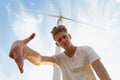 A sassy teenager on a blue sky background. Close-up of stylish hipster guy next to a windmill. Teenage years concept. Royalty Free Stock Photo