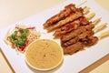 Satay meat in thick sticks with sweet peanut sauce & sliced raw vegetables at side