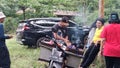 A satay seller with a motorbike is burning satay at the Watu Bahan Tourism Park, Pekalongan, Indonesia 23 November 2022