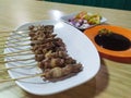 Satay on the white plate with tomatoes red onion and sweet soysauce Royalty Free Stock Photo