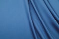 The sateen cut of blue fabric is spread out by the soft draped folds Royalty Free Stock Photo