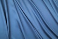 The sateen cut of blue fabric is spread out by the soft draped folds Royalty Free Stock Photo