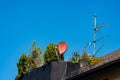 Satellite dish and antennas on a rooftop with greenery on sunny day Royalty Free Stock Photo