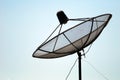 A satellite dish with blue sky and black pole