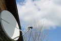 Satellite dish on a country house on a background of a blue sky with clouds. Royalty Free Stock Photo