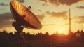 Satellite dish on ground facing sunset, with tower on background, stock photo Royalty Free Stock Photo
