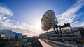 Satellite dish on the rooftop a modern office building, blue sky and setting sun Royalty Free Stock Photo