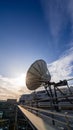 Satellite dish on the rooftop a modern office building, blue sky and setting sun Royalty Free Stock Photo