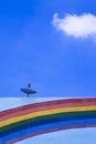 Satellite dish on top of the old building with rainbow stripes on building wall surface against blue sky Royalty Free Stock Photo
