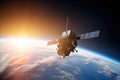 satellite, hovering above the earth with view of sunrise Royalty Free Stock Photo