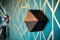 satellite speaker hanging on a wall with abstract, geometric wallpaper