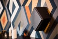 satellite speaker hanging on a wall with abstract, geometric wallpaper