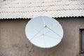 Satellite TV antenna on the wall of the house. Round white antenna receiver for radio signal. City antenna for