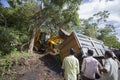Sathyamangalam, Tamil Nadu, India - June 24, 2015: An excavator lifting up a truck that has gone off the road, people watch on