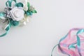 Satin braid of emerald and pink color intertwines on a white background. Near the wedding boutonniere. Royalty Free Stock Photo