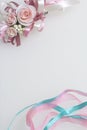 Satin braid of emerald and pink color intertwines on a white background. Near the wedding boutonniere. Royalty Free Stock Photo