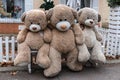 Satin-hearted teddy bear sits with friends on bench outside. Con