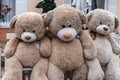 Satin-hearted teddy bear sits with friends on bench outside. Con