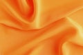 Satin silk fabric orange color for the background. Crumpled wavy silk. Texture of satin fabric Royalty Free Stock Photo