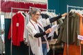 Woman looking at sketch touching hanging blouse