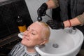 Satisfied adult attractive woman European customer barbershop in the process of washing hair with rain before cutting