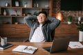 Satisfied adult japanese man resting in chair at table in office interior