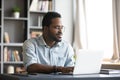 Satisfied African American man wearing glasses looking at computer screen