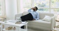 Satisfied African man relaxing seated on sofa at homeoffice