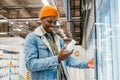 Satisfied African man in a supermarket selects bottled milk from the refrigerator and reads the composition of the