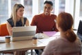 Satisfied afro-american male looking with smile at candidate for job while his caucasian female colleague have suspicious look