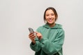 Satisfied asian brunette woman holding smartphone in hands, chatting with friends or making food order, online services Royalty Free Stock Photo