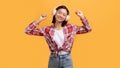 Satisfied asian lady in wireless headphone dancing, enjoying free time, listening music, isolated on yellow background Royalty Free Stock Photo