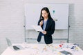 Content Asian businesswoman revising documents while standing by office table