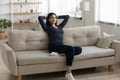 Satisfied Asian woman relaxing, stretching on couch at home