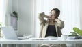 Satisfied asian young woman relaxing at her workplace and looking through the window at office Royalty Free Stock Photo