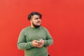 Satisfied attractive young hispanic man is using wireless earphones to listen to the music on his mobile phone, enjoying the Royalty Free Stock Photo